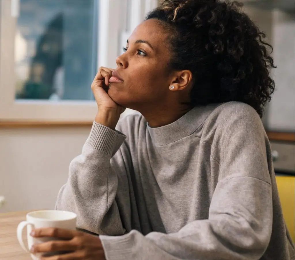 Beautiful woman is sitting alone in the kitchen and thinking
